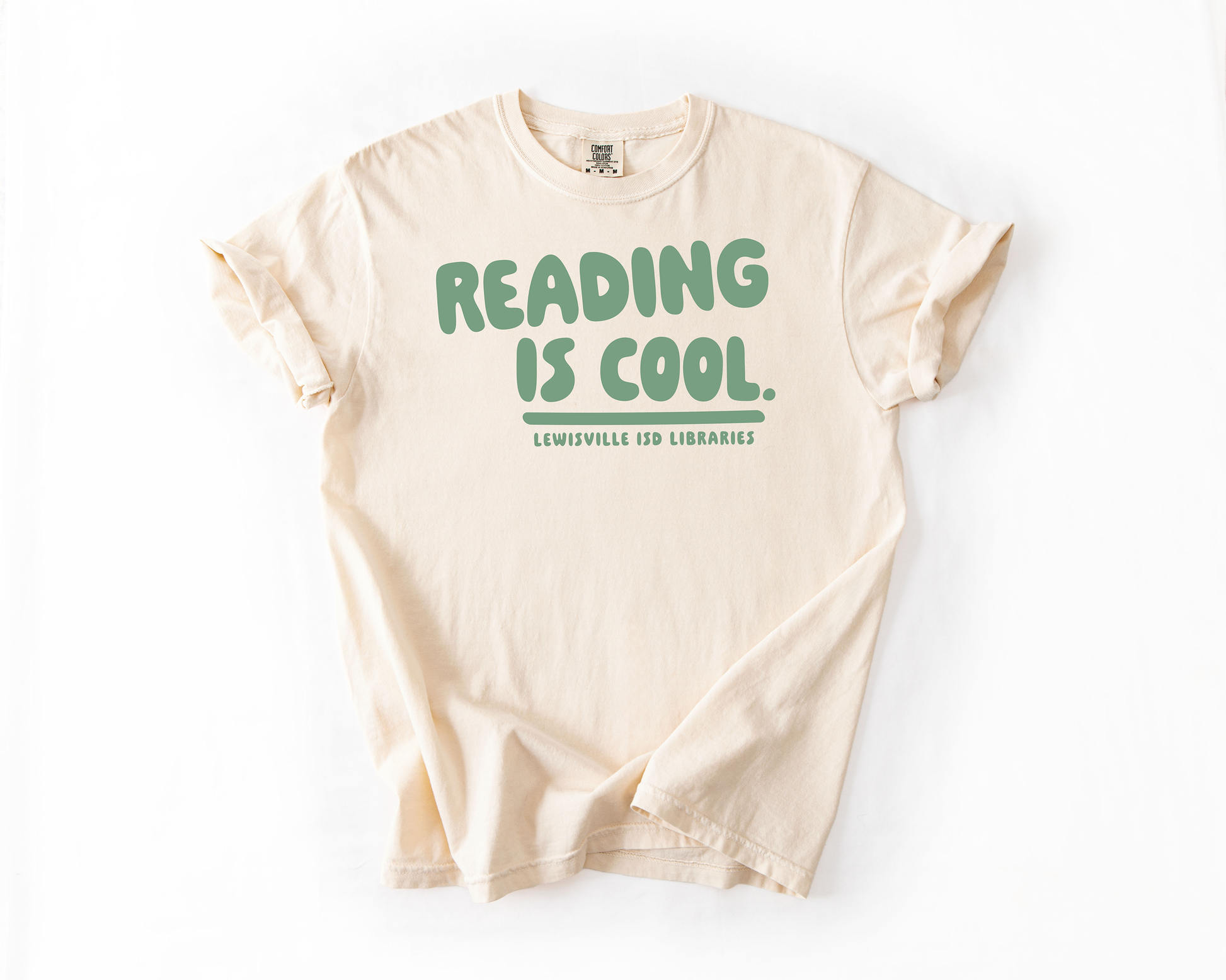 A cream-colored t-shirt with the text "READING IS COOL. LEWISVILLE ISD LIBRARIES" printed on it.