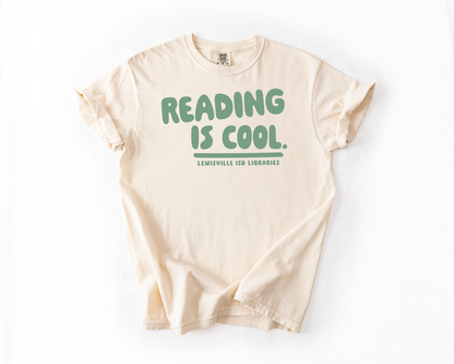 A cream-colored t-shirt with the text "READING IS COOL. LEWISVILLE ISD LIBRARIES" printed on it.