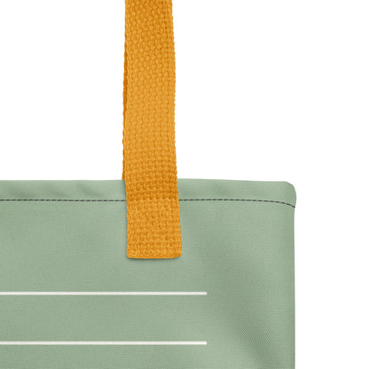 A close-up view of a green fabric bag with a yellow handle, showing the handle and a white line on the fabric.