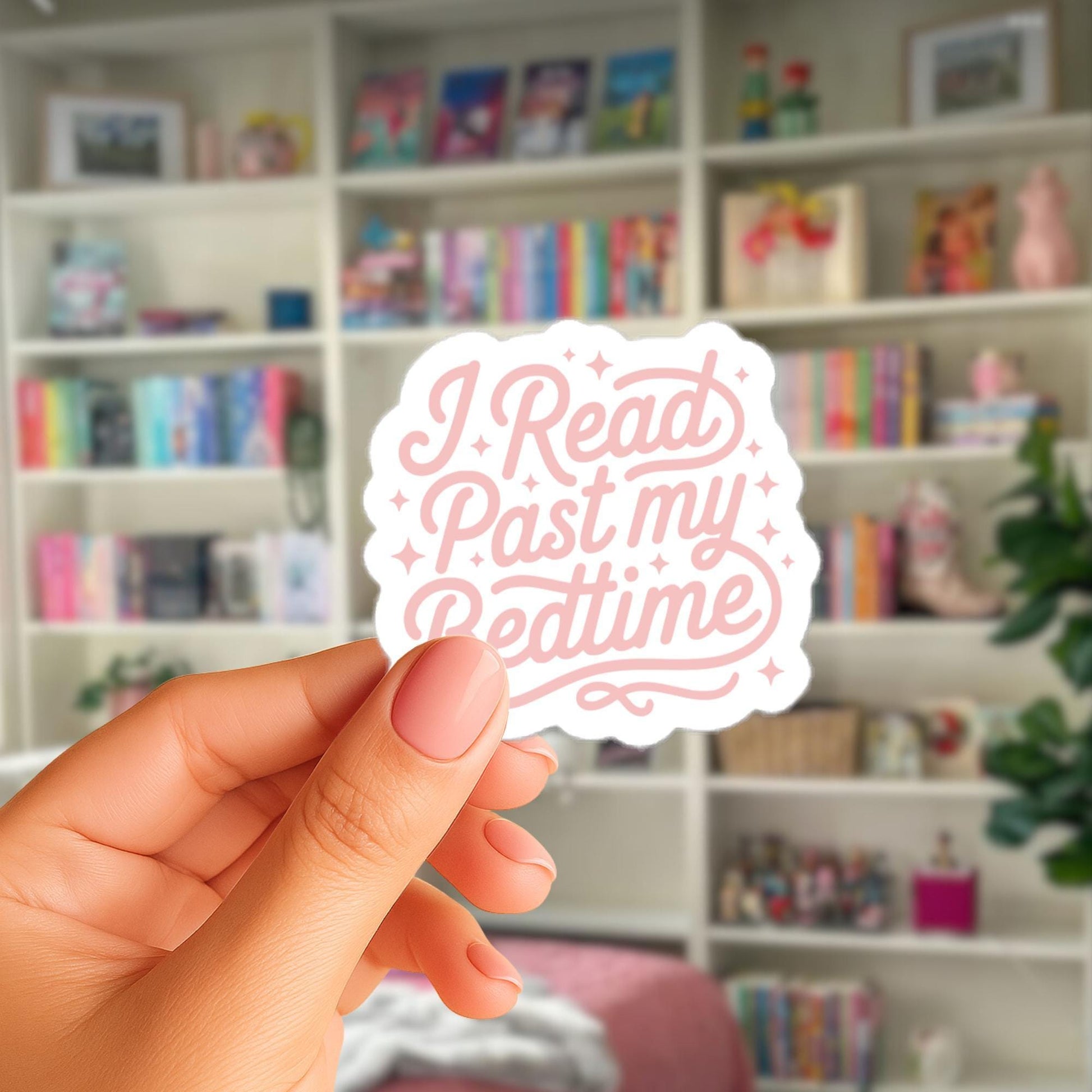 A hand holding a sticker with the text "I Read Past My Bedtime" in a room with bookshelves filled with books.