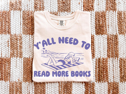 A white t-shirt with a graphic design and text printed on it, laid out on a woven mat.