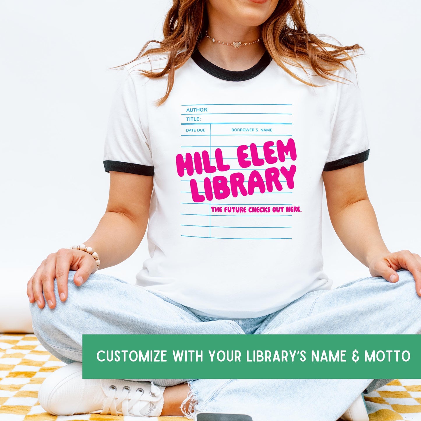 A woman wearing a white t-shirt with a graphic design of a library book and the text "HILL ELEM LIBRARY" printed on it.