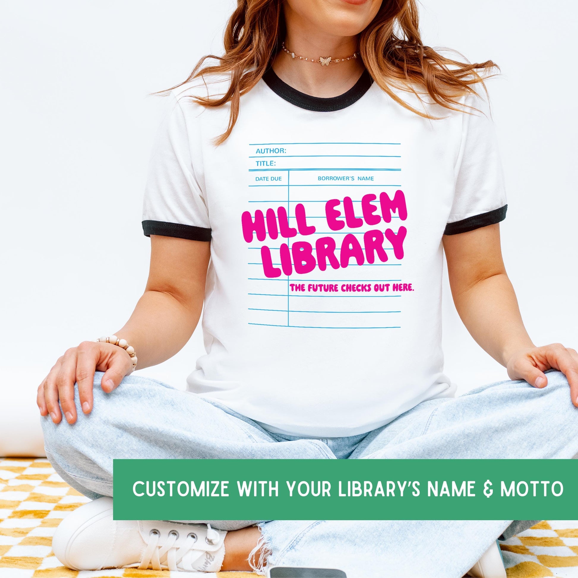 A woman wearing a white t-shirt with a graphic design of a library book and the text "HILL ELEM LIBRARY" printed on it.
