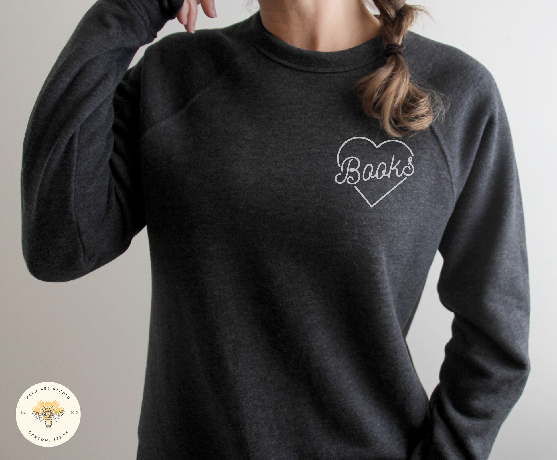 A person wearing a gray sweatshirt with the word "Books" written on it in white text.