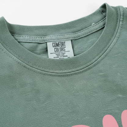 A green t-shirt with a label that reads "Comfort Colors" attached to the collar.