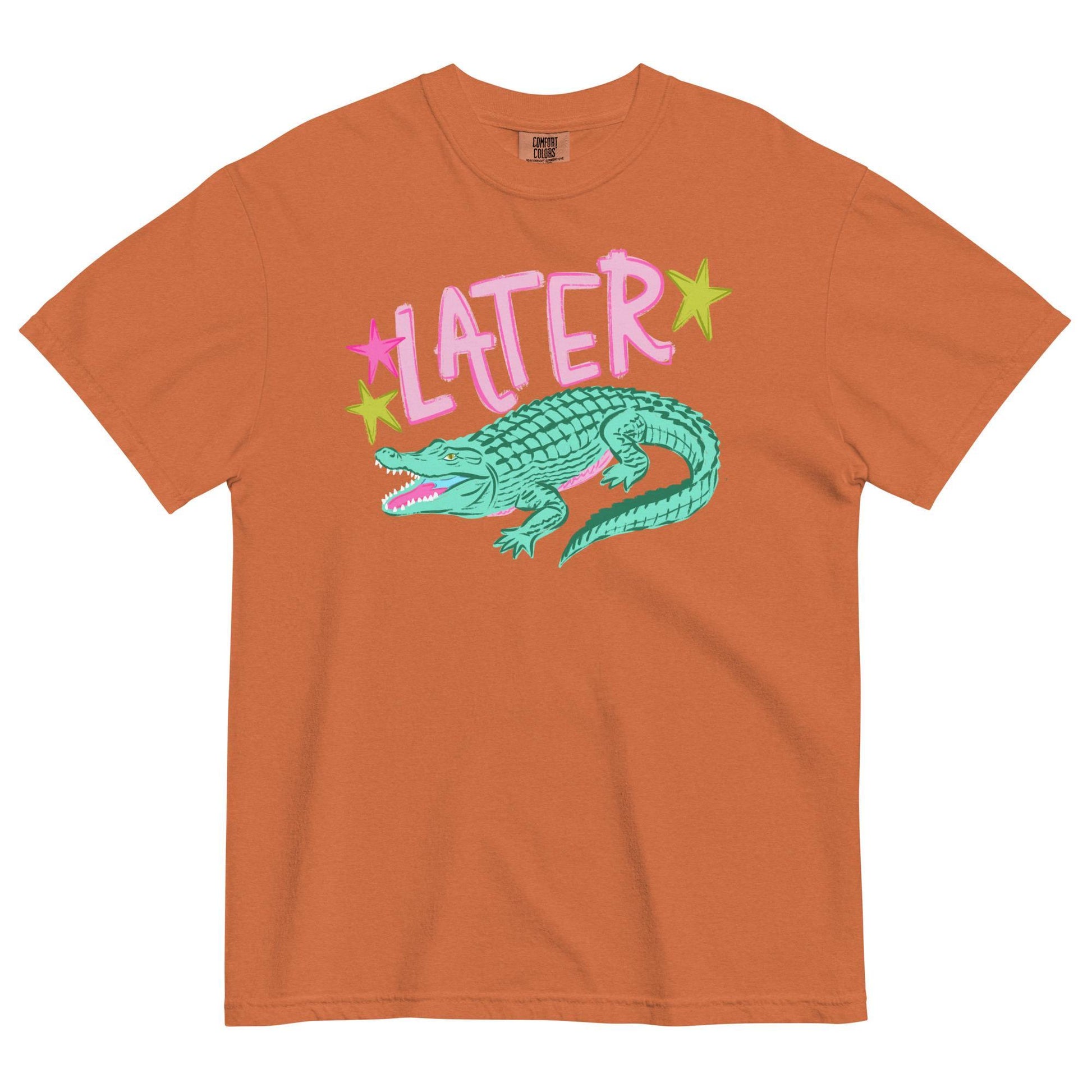 An orange t-shirt with a graphic design featuring a green alligator and the word "later" written above it.