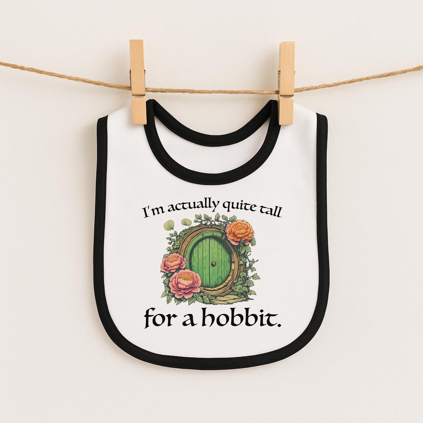 A white bib with a black border and a green door with a green handle, along with a quote that says "I'm actually quite tall for a hobbit."