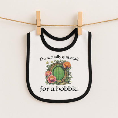 A white bib with a black border and a green door with a green handle, along with a quote that says "I'm actually quite tall for a hobbit."