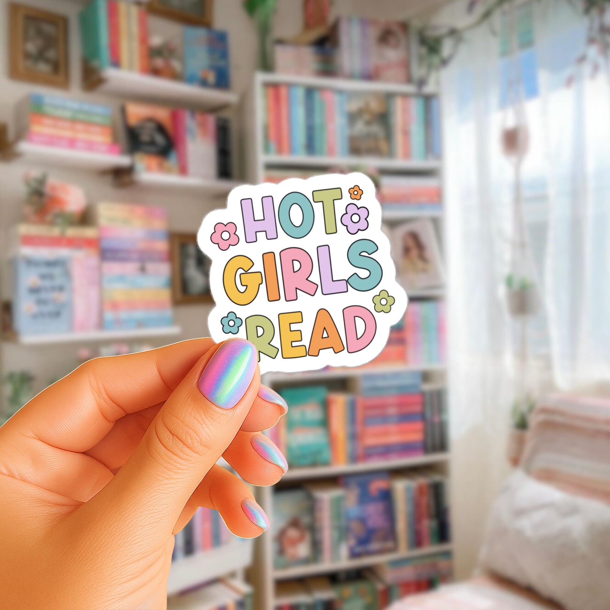 A hand holding a sticker with the text "HOT GIRLS READ" in a colorful, playful font.